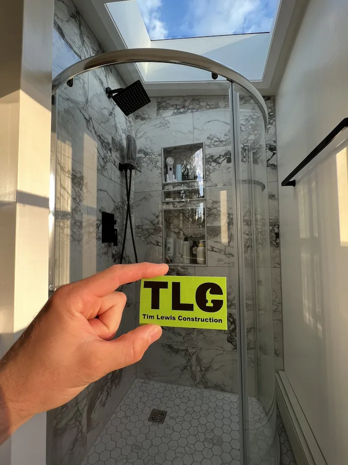 A hand holding TLC business card in finished bathroom.